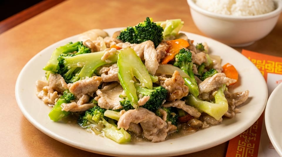 A plate of chicken and broccoli stir-fry with carrots and mushrooms, served with white rice.