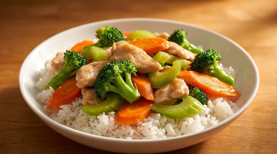 Chicken stir-fry with broccoli, carrots, and celery over white rice in a bowl.